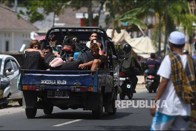 Sejumlah wisatawan mancanegara menumpang mobil bak terbuka ketika menuju Mataram di Lombok Utara, NTB, Senin (6/8). Sedikitnya 700 orang wisatawan bersama warga setempat dievakuasi dari Gili Trawangan, Gili Air dan Gili Meno menuju Pelabuhan Bangsal mengantisipasi terjadinya gempa susulan.
