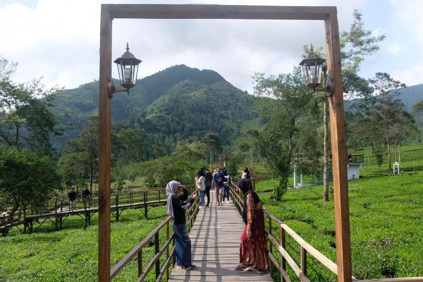 Sejumlah wisatawan menyusuri jembatan kayu di kawasan wisata alam Patean, kompleks agrowisata kebun teh Tambi, Kejajar, Wonosobo, Jateng, Kamis (12/5/2022). Tren pariwisata setelah pandemi yaitu yang berkelanjutan berbasis masyarakat.