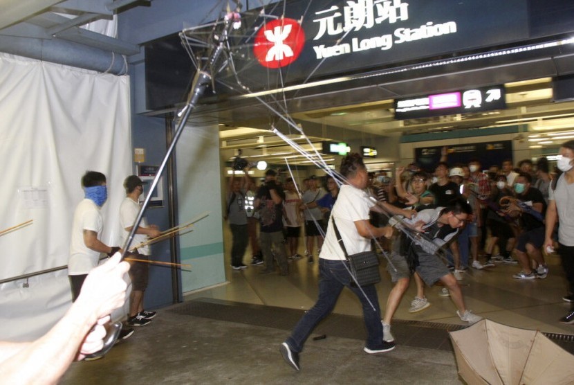 Sekelompok laki-laki berkemeja putih bersenjatakan tongkat logam dan kayu menyerang penumpang di stasiun kereta bawah tanah di New Territory di Hong Kong, Ahad (21/7).