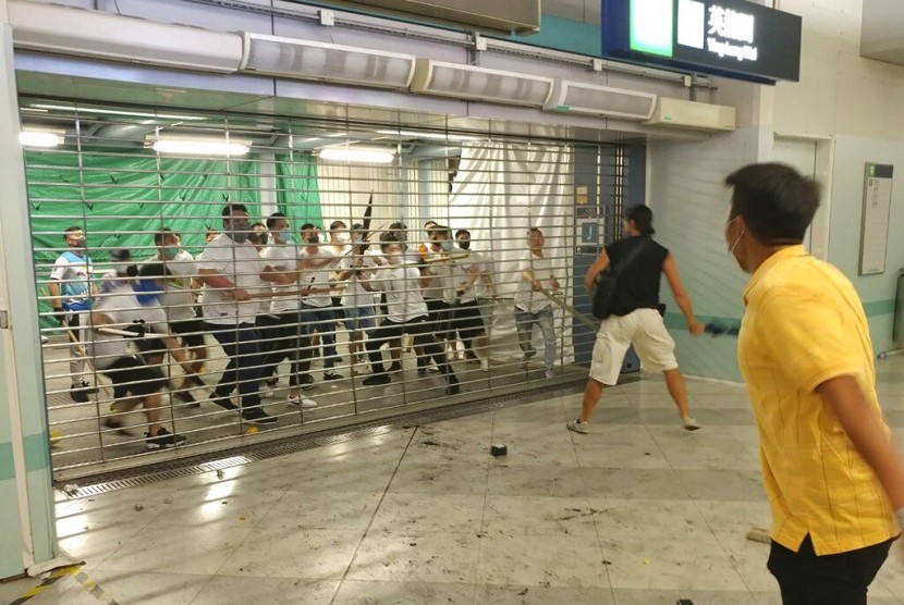 Sekelompok laki-laki berkemeja putih bersenjatakan tongkat logam dan kayu menyerang penumpang di stasiun kereta bawah tanah di New Territory di Hong Kong, Ahad (21/7).