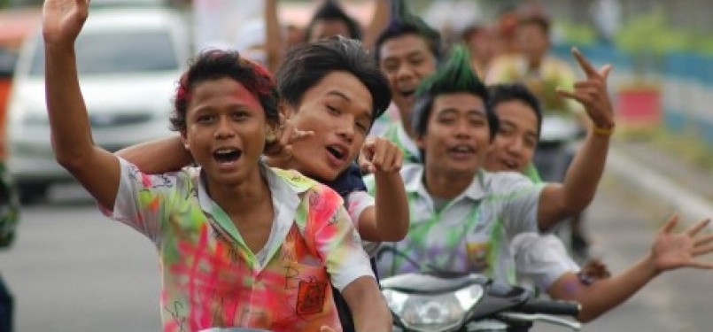 Sekumpulan siswa-siswi SMP berarak-arakan menggunakan motor dengan baju seragam penuh coretan, merayakan kelulusan mereka.