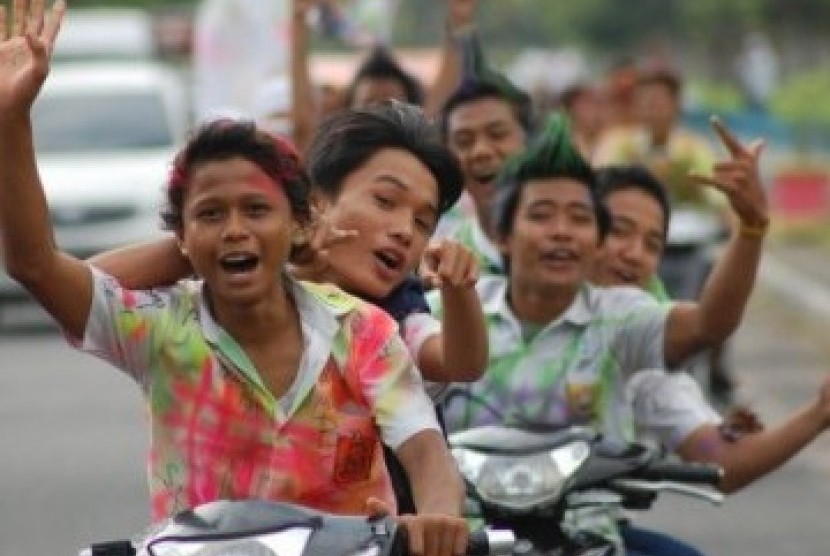 Sekumpulan siswa-siswi SMP berarak-arakan menggunakan motor dengan baju seragam penuh coretan, merayakan kelulusan mereka.