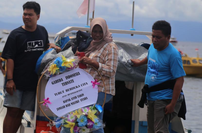   Seorang keluarga  jamaah haji yang meninggal di debarkasi Makassar membawa karangan bunga  ucapan bela sungkawa bagi kerabatnya yang meninggal dalam perjalanan pulang haji dengan memaskapai Garuda .