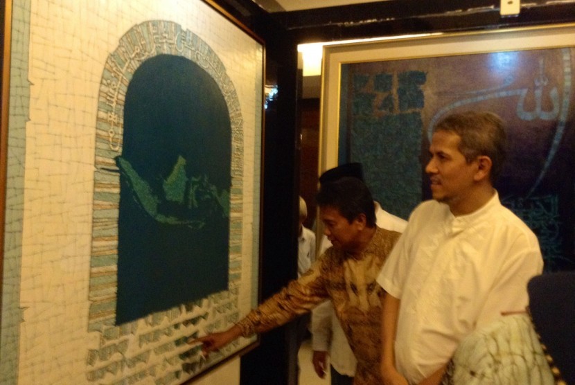Seniman kaligrafi Islam, Syaiful Adnan (kiri), menjelaskan salah satu karyanya di Jakarta, Rabu (16/4).