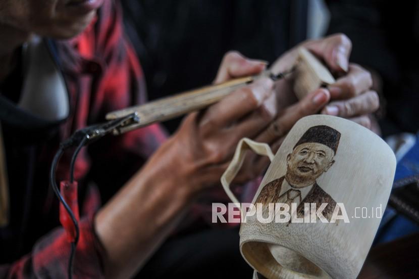 Seniman menyelesaikan lukisan dengan bahan baku kayu saat pameran UKM Jabar Paten di Ciumbuleuit, Bandung, Jawa Barat. Pemerintah Provinsi Jawa Barat mulai menyalurkan bantuan sosial (Bansos) berupa sembako dan uang tunai kepada seniman dan budayawan yang terdampak PPKM darurat. 