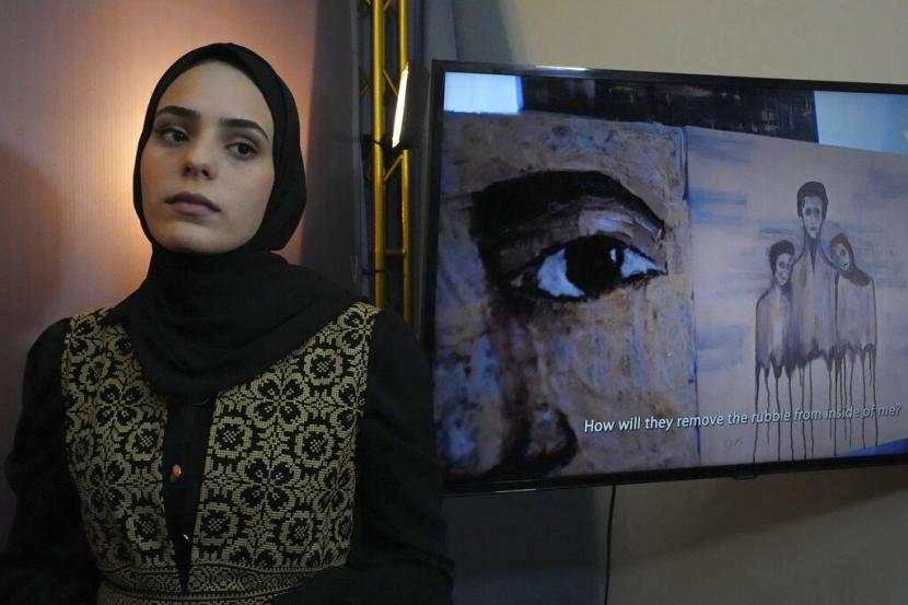 Seniman Palestina Zainab al-Kawlak berdiri di samping salah satu lukisannya dalam pamerannya. Perempuan di Gaza, kini telah memiliki sebuah aplikasi di telepon genggam mereka untuk melaporkan kekerasan dalam rumah tangga (KDRT) secara anonim.