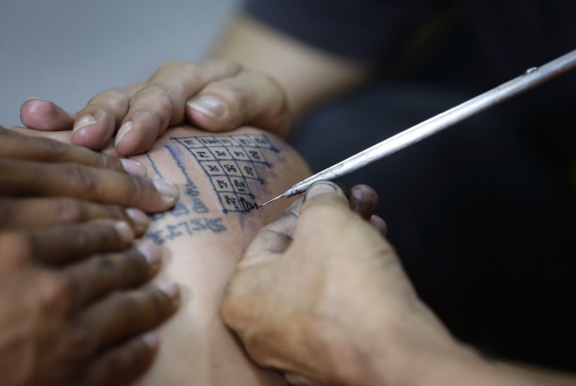 Seniman tato sedang membuat tato.