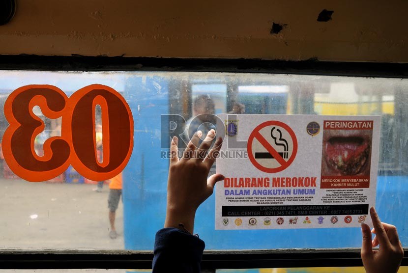  Seorang aktivis Koalisi Warga Untuk Jakarta Bebas asap Rokok (Smoke Free Jakarta) menempelkan stiker penanda larangan merokok di angkutan umum di Terminal Senen Jakarta, Selasa (21/5).    (Republika/Prayogi)