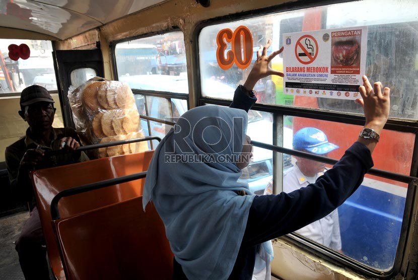  Seorang aktivis Koalisi Warga Untuk Jakarta Bebas asap Rokok (Smoke Free Jakarta) menempelkan stiker penanda larangan merokok di angkutan umum di Terminal Senen Jakarta. (Republika/Prayogi)