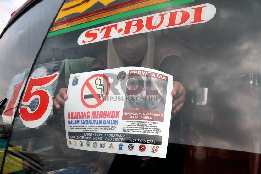  Seorang aktivis Koalisi Warga Untuk Jakarta Bebas asap Rokok (Smoke Free Jakarta) menempelkan stiker penanda larangan merokok di angkutan umum di Terminal Senen Jakarta, Selasa (21/5).    (Republika/Prayogi)