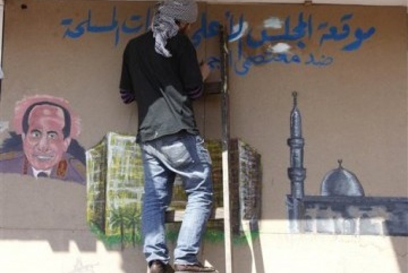 Seorang aktivis Mesir menulis grafiti anti-militer di sebuah bangunan dekat Tahrir Square, Kairo.