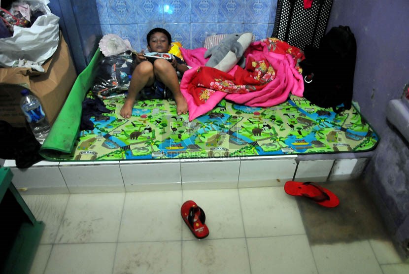    Seorang anak berbaring di dalam rumahnya yang terendam banjir di kawasan pemukiman Kampung Melayu Besar, Jakarta, Rabu (29/1).   (Republika/Prayogi)