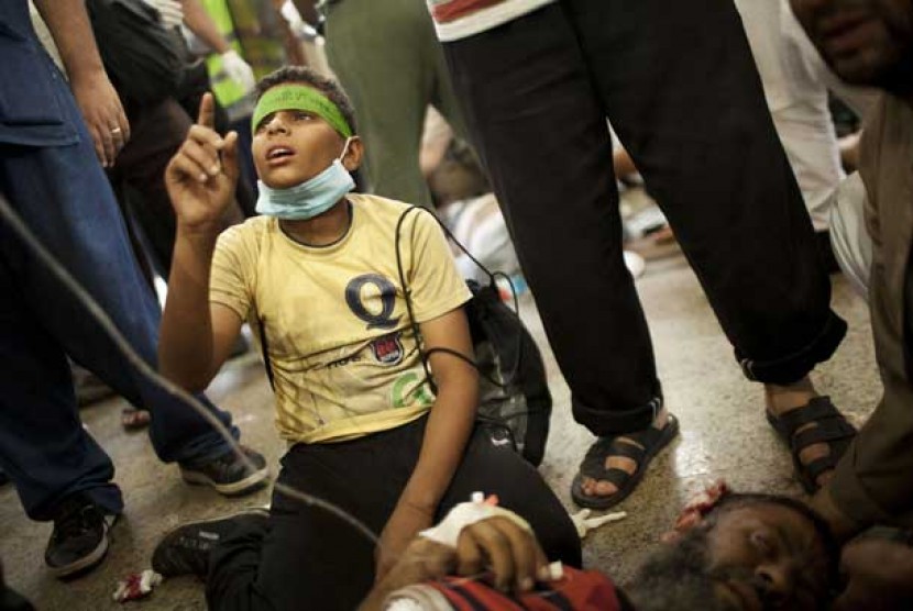 Seorang anak berdiri di atas lututnya sambil berdoa di samping ayahnya yang tewas, dalam bentrokan pendukung Presiden Mursi dengan pasukan keamanan di Nasr City, Kairo, Sabtu (27/7).