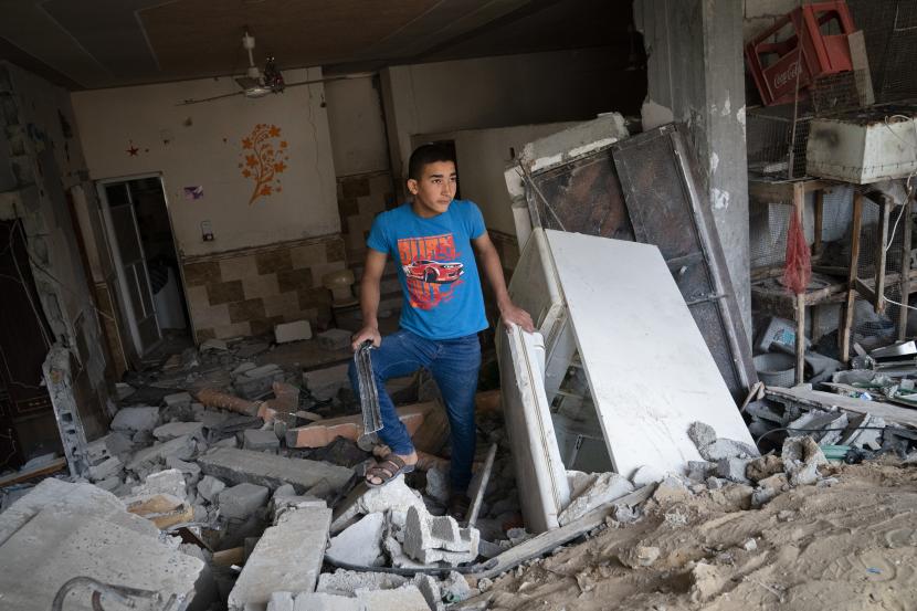 Seorang anak berdiri di dalam gedung yang rusak parah di dekat kawah tempat rumah Ramez al-Masri dihancurkan oleh serangan udara sebelum gencatan senjata tercapai setelah perang 11 hari antara penguasa Hamas di Gaza dan Israel, Minggu, 23 Mei. , 2021, di Beit Hanoun, Jalur Gaza utara.