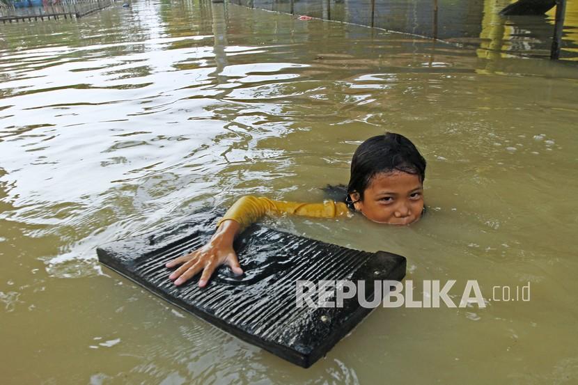 Seorang anak bermain air saat banjir di Desa Karangligar, Karawang, Jawa Barat, Jumat (5/11/2021). Banjir yang melanda di wilayah itu disebabkan meluapnya air sungai Cibeet karena tingginya intensitas hujan yang mengakibatkan ratusan rumah terendam banjir.