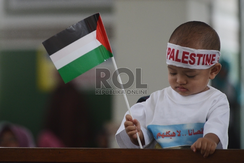 Seorang anak bermain bendera Palestina saat penandatanganan surat pernyataan bersama yang diasosiakan oleh Asia Pasific Comunity for Palestine (ASPAC) usai Shalat Jumat bersama di Masjid Al Azhar, Jumat (17/9). 