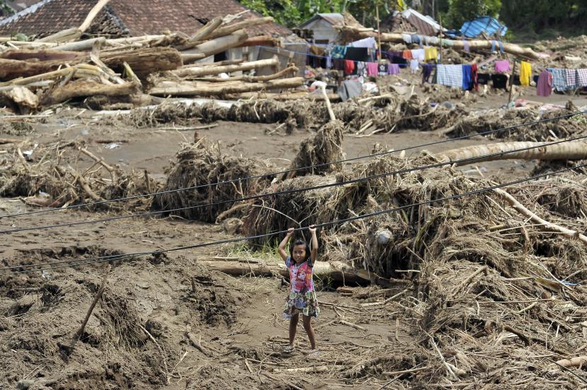 Seorang anak bermain di area rumahnya yang dipenuhi material kayu dan lumpur pascabanjir bandang di Bali (ilustrasi).  BPBD Bali merangkum titik rawan bencana tanah longsor pada musim hujan 2023.
