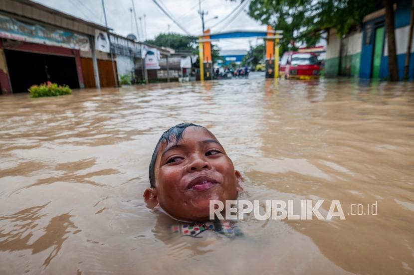 Seorang anak bermain saat banjir di Rangkasbitung, Lebak, Banten, Sabtu (3/4/2021). Menurut data BPBD Kabupaten Lebak sebanyak 63 rumah dari tiga kecamatan di Lebak terendam banjir akibat diguyur hujan dengan intensitas tinggi yang terjadi sejak Jumat (2/4/2021). 