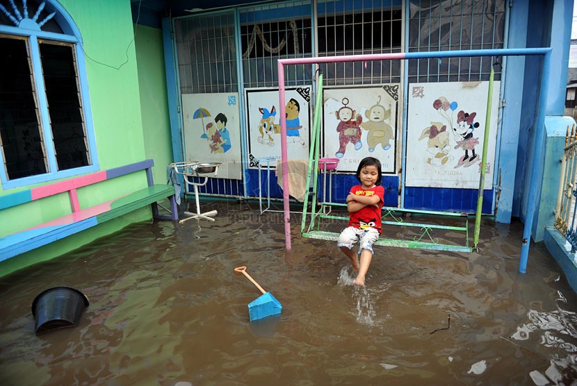   Seorang anak bermain saat banjir merendam perumahan Jatikramat Indah di Bekasi, Jawa Barat, Jumat (28/3). (Republika/Edwin Dwi Putranto)