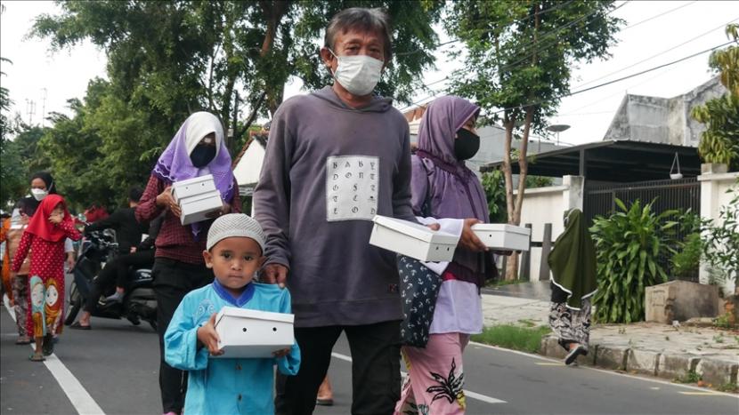 Seorang anak bersama sejumlah warga dewasa  di tengah suasana pandemi dengan tanpa mengenakan masker ikut antre untuk mendapatkan makanan berbuka puasa di Cempaka Putih di Jakarta, Indonesia pada 16 April, 2021. (ilustrasi)