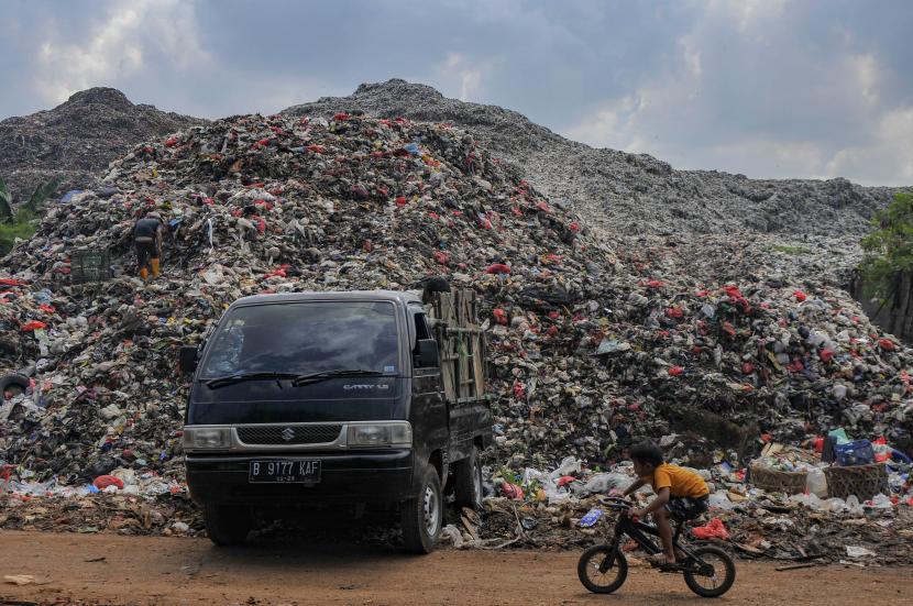 Seorang anak bersepeda melintasi tumpukan sampah di TPA (Tempat Pembuangan Akhir) Burangkeng, Setu, Kabupaten Bekasi, Jawa Barat. TPA Burangkeng Bekasi kembali beroperasi usai kejadian longsor gunungan sampah.
