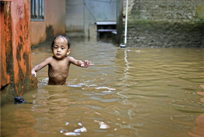 Seorang anak berusaha melintasi genangan banjir yang menggenangi sebuah kawasan di Jakarta. (ilustrasi)