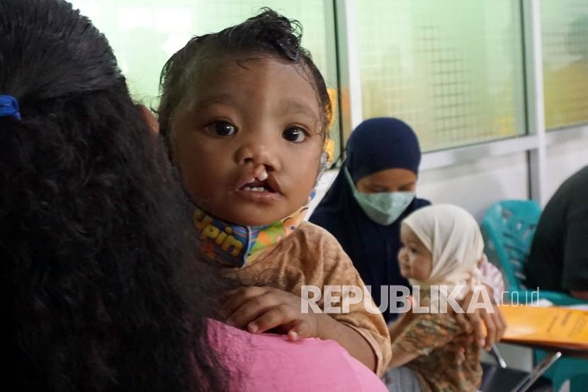Seorang anak digendong Ibunya antre untuk pemeriksaan kesehatan sebelum pelaksanaan operasi bibir sumbing.