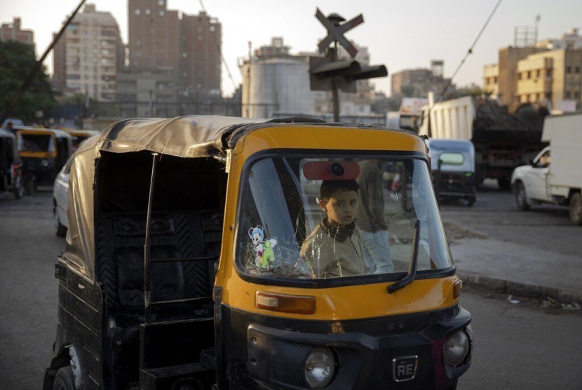 Seorang anak duduk di atas tuk-tuk di daerah kumuh Kairo, Mesir, Rabu (4/12). Pemerintah Mesir berencana menghapus tuk-tuk dan menggantinya dengan minivan.