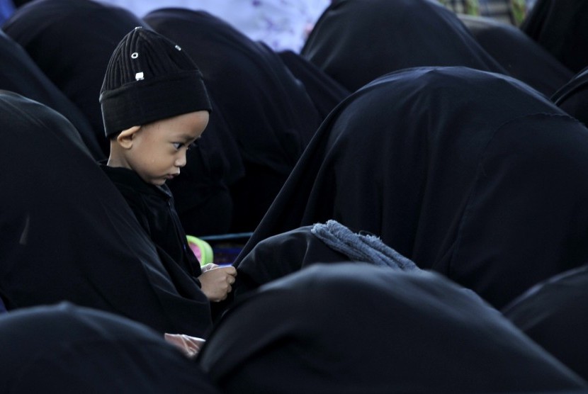 Seorang anak jamaah An Nadzir bermain di dekat ibunya saat melakukan salat Idul Adha di Kampung Jamaah An Nadzir, Danau Mawang Gowa, Sulawesi Selatan, Selasa (22/9).