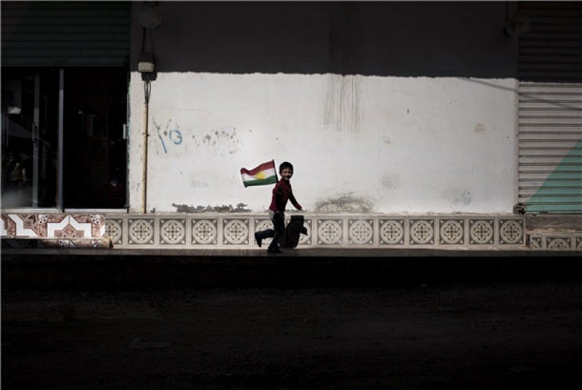  Seorang anak kecil memegang bendera Kurdi di kota Ras Al Ayn di Suriah. (ilustrasi) 