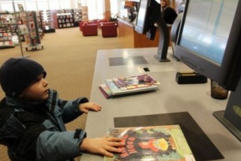 Seorang anak kecil sedang menggunakan fasilitas teknologi di sebuah perpustakaan. (ilustrasi)