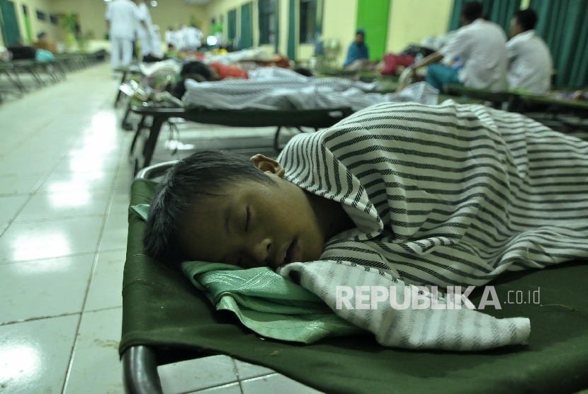 Seorang anak korban banjir tertidur dilokasi pengungsian di Korem 062/Tarunanegara, Jl Bratayuda, Kabupaten Garut, Kamis (22/9) Dini hari. 