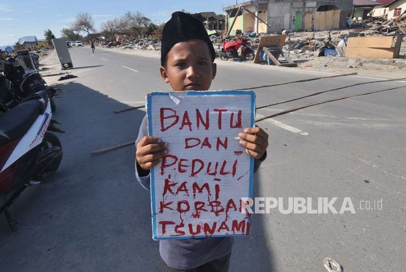 Seorang anak korban gempa dan tsunami berdiri mengharapkan sumbangan dari pengendara yang lewat di Palu, Sulawesi Tengah, Senin (8/10).