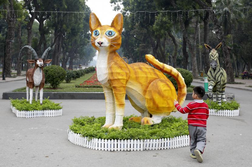 Seorang anak laki-laki berjalan menuju patung kucing di taman Thong Nhat menjelang Tahun Baru Imlek mendatang, atau Tet di Hanoi, Vietnam, 20 Januari 2023. Tet dianggap sebagai perayaan terpenting dalam budaya Vietnam. Tahun ini, Tet jatuh pada 22 Januari 2023, menandai awal tahun Kucing.