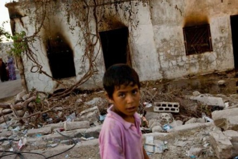 Seorang anak laki-laki Suriah berjalan melewati sebuah rumah yang terbakar di desa Taremseh.