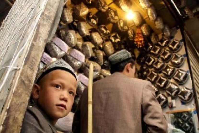 Studi: Kebijakan China Cegah Jutaan Kelahiran Muslim Uighur. Seorang anak laki-laki Xinjiang membantu ayahnya berjualan peci khas Muslim Uighur.
