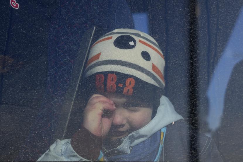 Seorang anak melihat melalui jendela bus yang membawa pengungsi yang melarikan diri dari konflik 