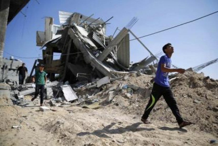 Seorang anak melintasi reruntuhan bangunan yang hancur dalam serangan Israel.