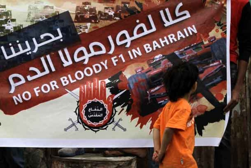 Seorang anak melintasi sebuah spanduk yang menolak digelarnya lomba Formula Satu di Bahrain, Sabtu (6/4).