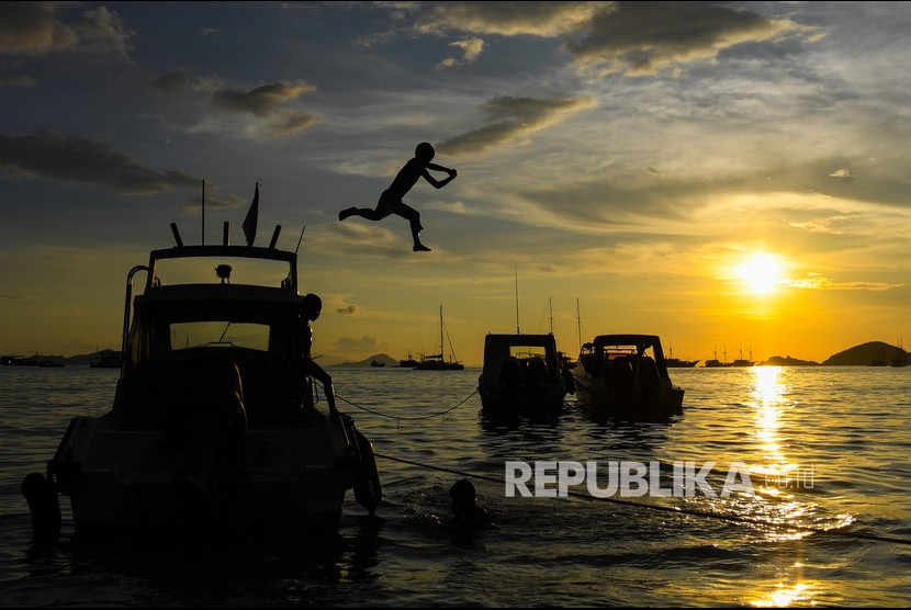Seorang anak melompat dari atas kapal di Pantai Pede, Labuan Bajo, Manggarai Barat, Nusa Tenggara Timur, Sabtu (19/6/2021). Sebagian warga di Labuan Bajo menjadikan pantai tersebut sebagai wisata alternatif pada akhir pekan.