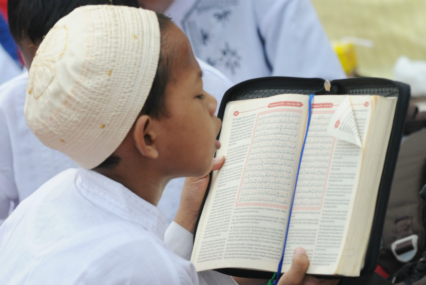  Seorang anak membaca Alquran dalam kegiatan khataman secara massal menyambut Ramadhan di Lapangan Tugu Proklamasi, Jakarta, Kamis (19/7). (Aditya Pradana Putra/Republika)