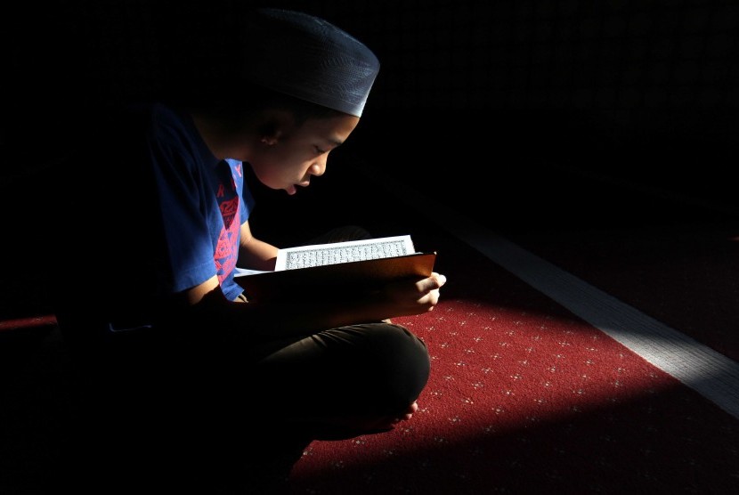 Seorang anak  membaca Alquran di Masjid Raya Al Mashun, Medan, Sumatra Utara, Minggu (12/6).