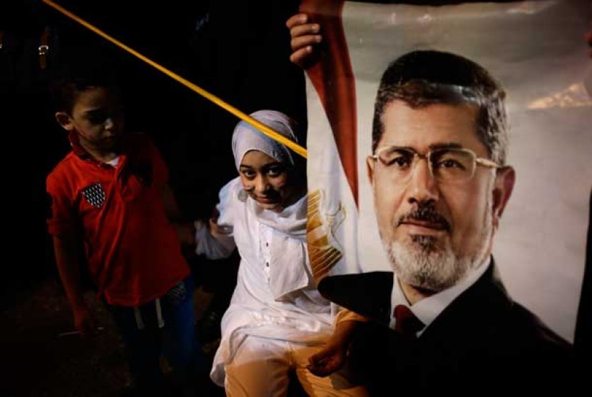 Seorang anak membawa poster Presiden Muhammad Mursi di kawasan masjid Rabaah al-Adawiya di Nasr City, Kairo,   Rabu (31/7). 