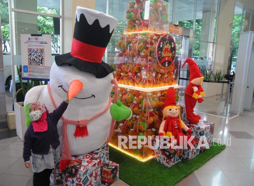 Seorang anak memegang boneka salju di Mall Botani Square, Kota Bogor, Jawa Barat. Pemerintah pada Selasa (7/12) membatalkan kebijakan PPKM Level 3 di masa libur Natal dan tahun baru.