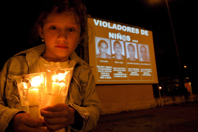  Seorang anak memegang lilin berdiri disamping foto empat orang yang dihukum dalam kasus pelecehan seksual anak.     (ilustrasi)