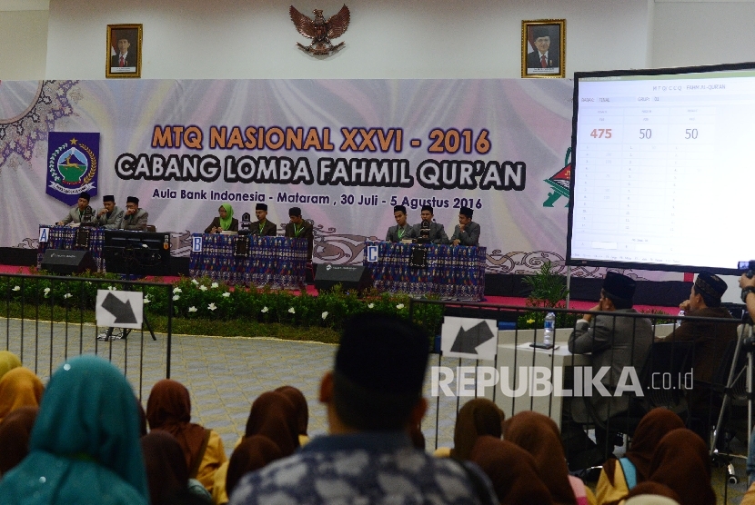 Seorang anak memotret tiga grup Kafilah yang mengikuti final MTQ Nasional ke XXVI cabang Fahmil Quran (Cerdas Cermat) di Aula Bank Indonesia, Kota Mataram, Nusa Tenggara Barat, Kamis (4/8).