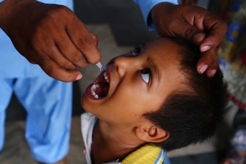 Seorang anak mendapatkan vaksin polio dari petugas kesehatan di Karachi, Pakistan. Vaksin TBC dan polio terpantau dapat mengurangi tingkat keparahan penyakit Covid-19.