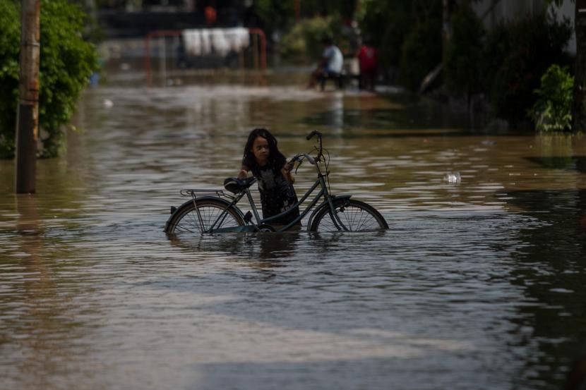 Seorang anak mendorong sepeda saat melintasi banjir yang menggenangi perkampungan di Pucang Sawit, Solo, Jawa Tengah, Sabtu (22/10/2022). Banjir tersebut disebabkan meluapnya air sungai Bengawan Solo karena hujan deras yang terjadi Jumat (21/10) sore hingga malam.