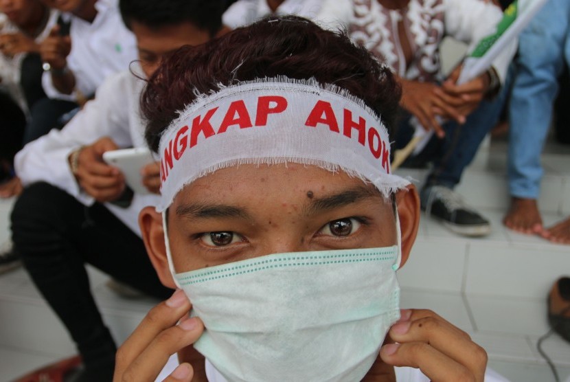 Seorang anak menggunakan ikat kepala saat ikut berunjuk rasa mengecam Gubernur DKI Jakarta Basuki Tjahaja Purnama atau Ahok di Medan, Sumatra Utara, Jumat (14/10). 