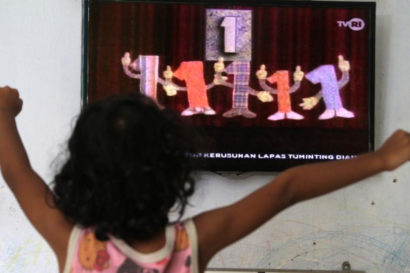 Seorang anak menonton televisi siaran perdana Pendidikan Anak Usia Dini di TVRI. Guru PAUD Rumah Aneuk Nanggroe mengunjungi rumah siswanya secara bergiliran untuk memastikan kelangsungan kegiatan belajar mengajar.
